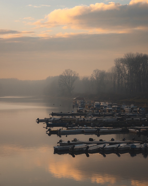 Majestic foggy morning on lake harbor with fishing boats
