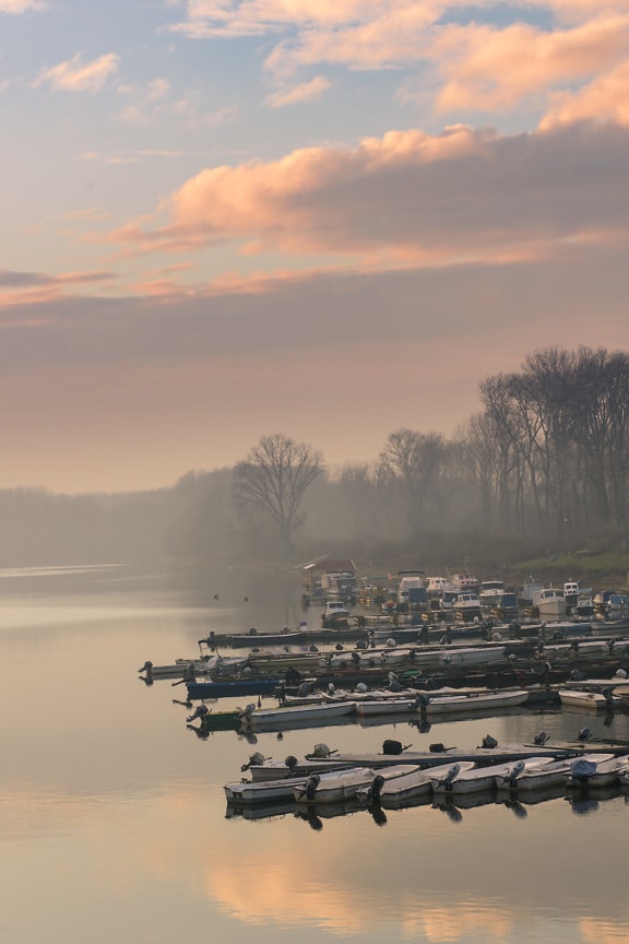 Majestic dawn over lakeside harbor with fishing boats