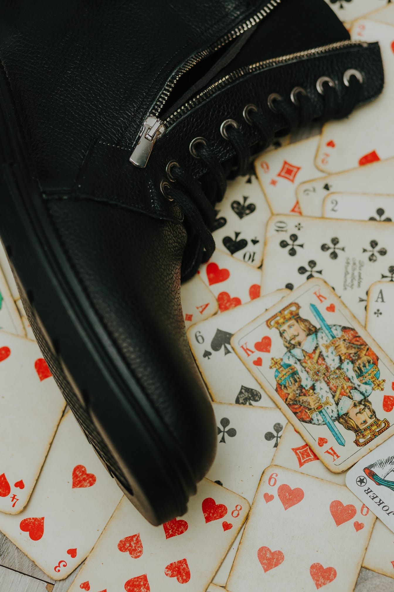 Black leather boot on old fashioned playing card