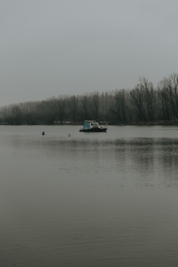 Small fishing boat on river in foggy morning