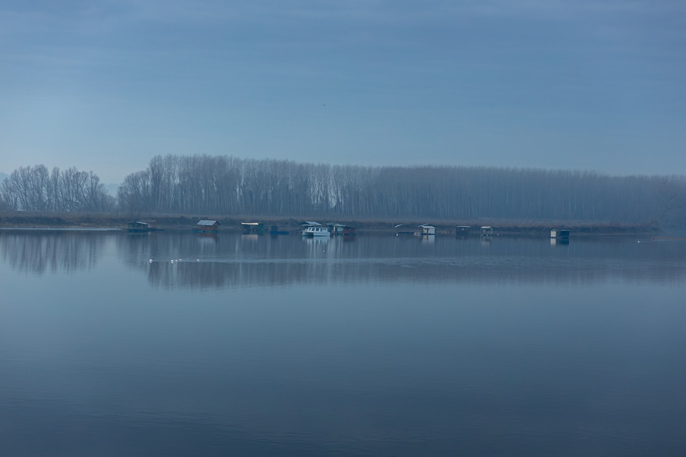 Buổi tối sương mù trên hồ với những nhà thuyền ở xa vào lúc hoàng hôn