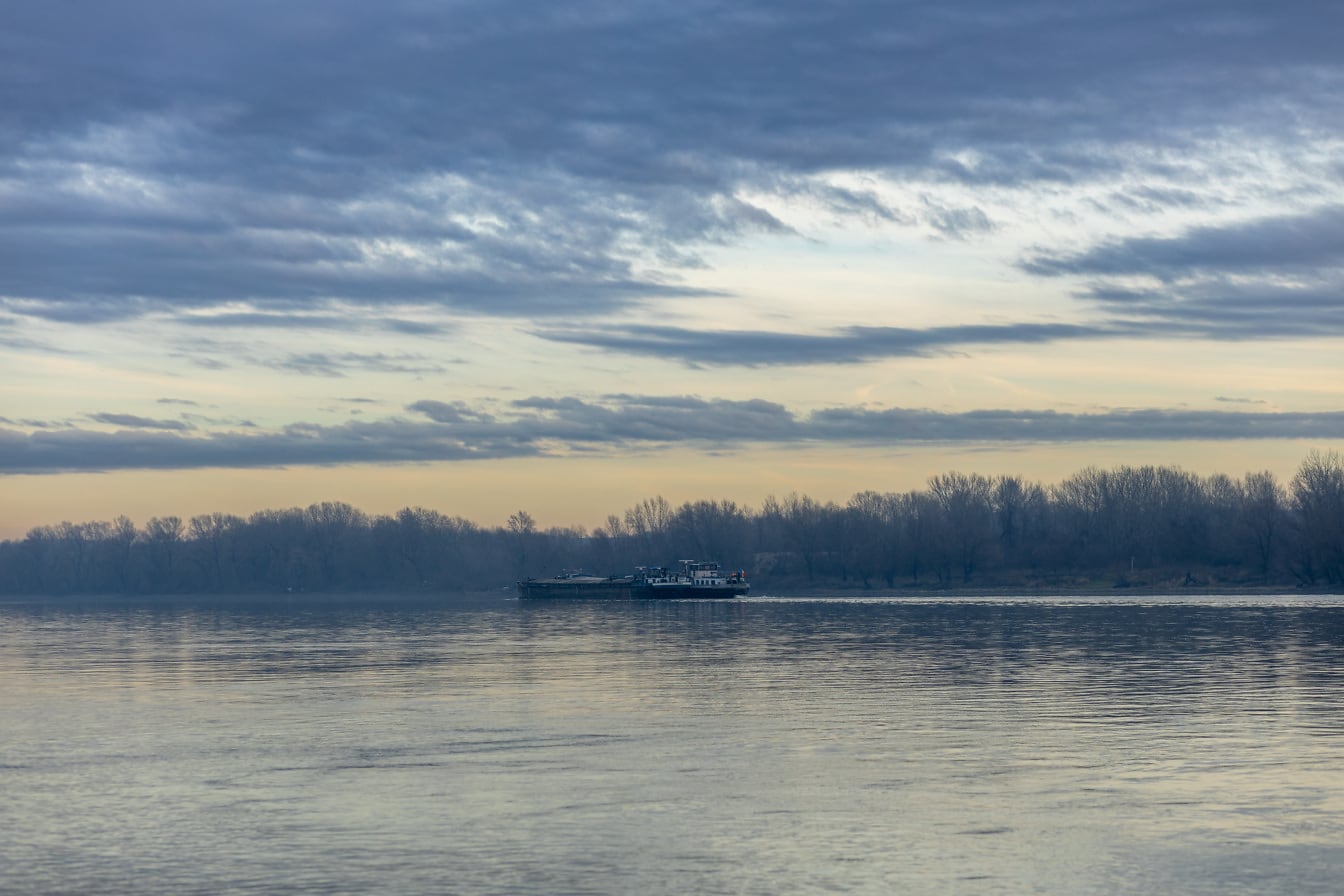 Φορτηγίδα στον ποταμό Δούναβη στο λυκόφως με συννεφιασμένο ουρανό