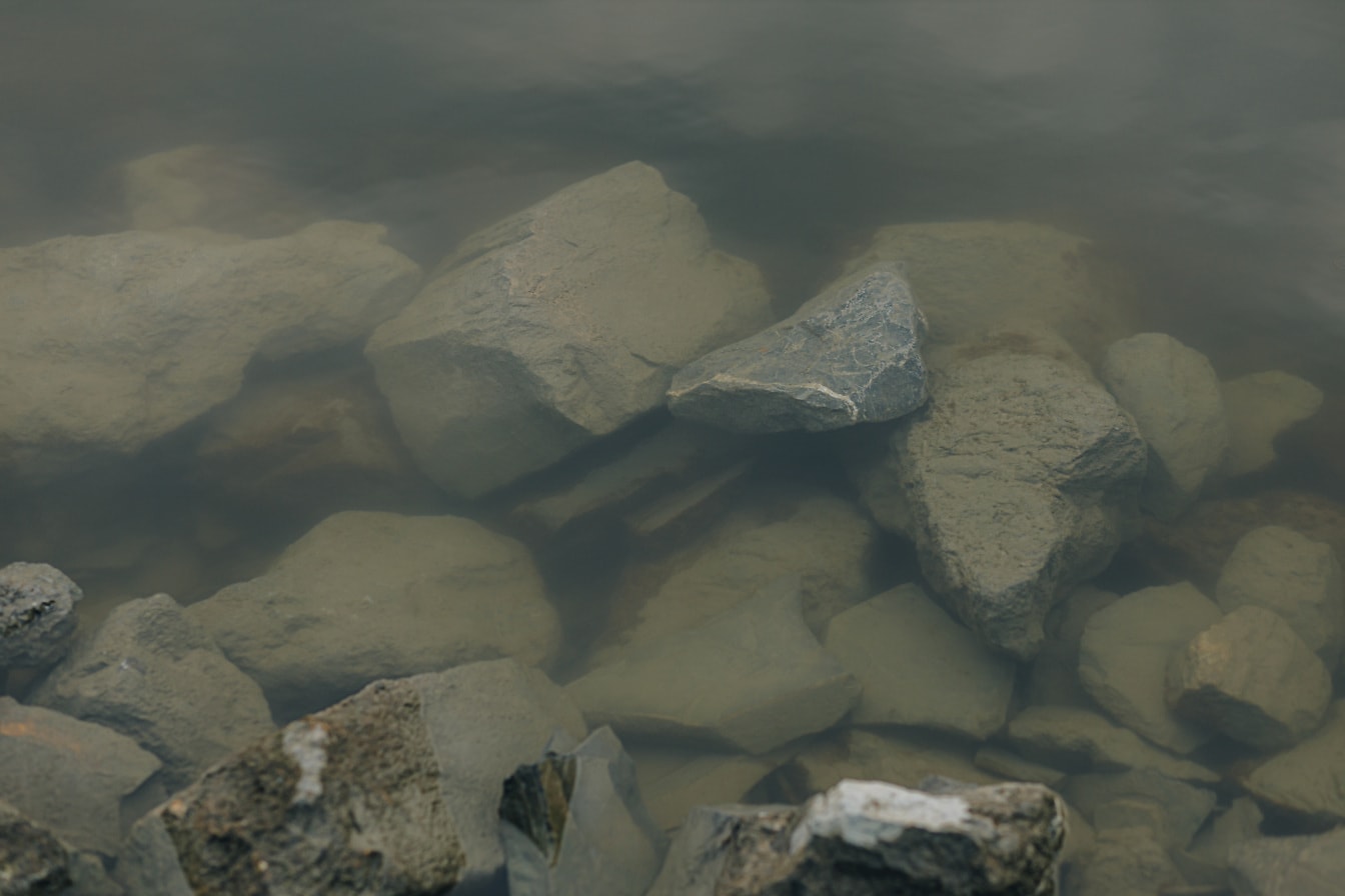 Големи скали на речното корито на брега на реката под водата