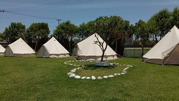 Beautiful lawn with heart shaped stones and white tents in campsite