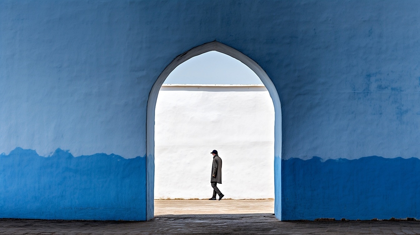 Uzakta yürüyen kişi ile koyu mavi duvar kapısı