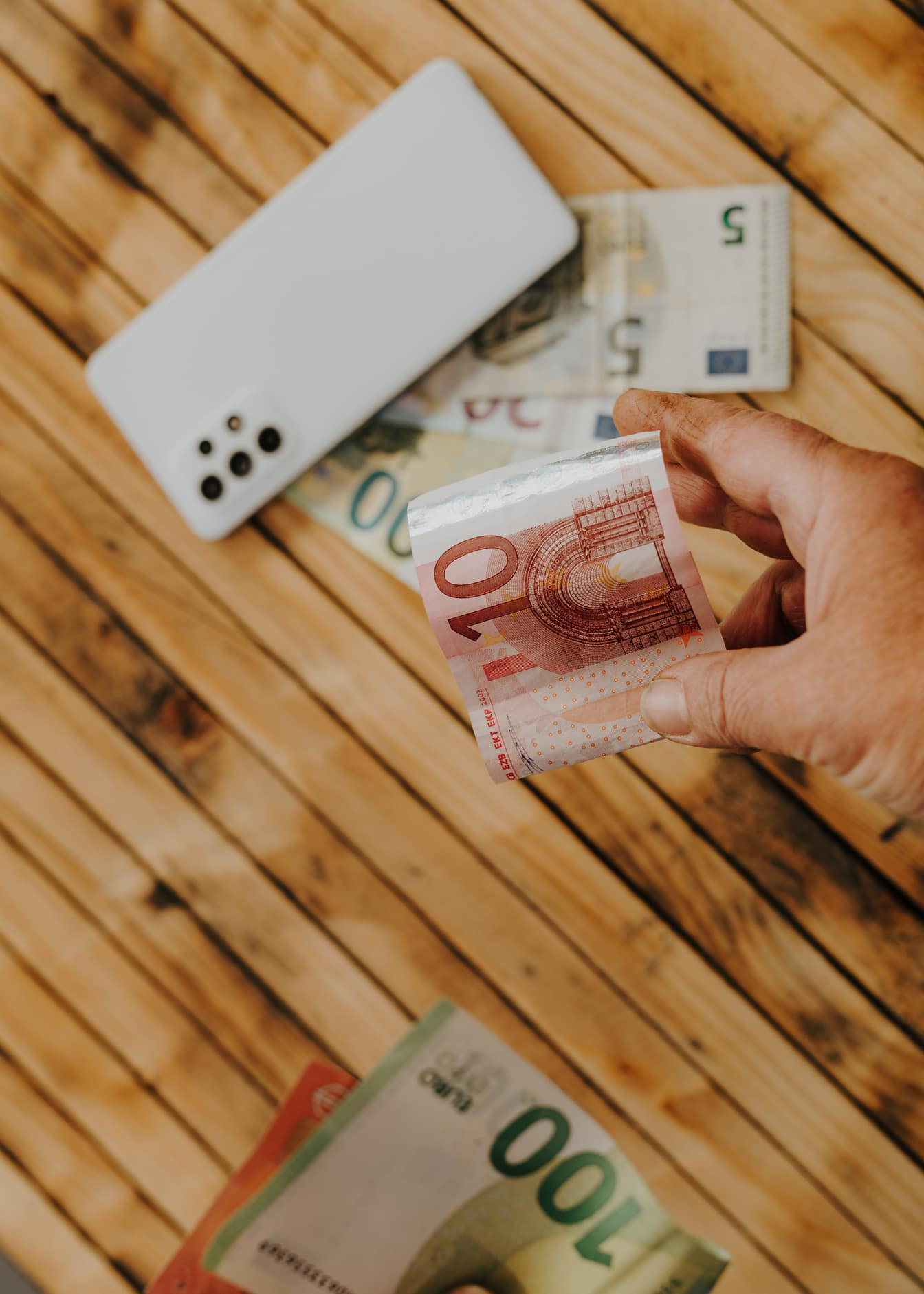 Fókuszban a tíz eurós (€10) bankjegyet tartó kéz