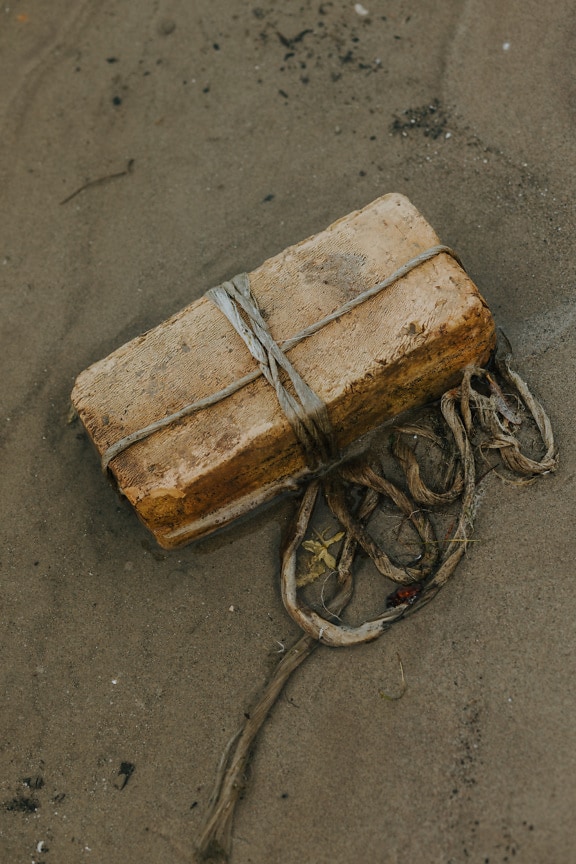 Light brown brick in nylon rope on wet sand