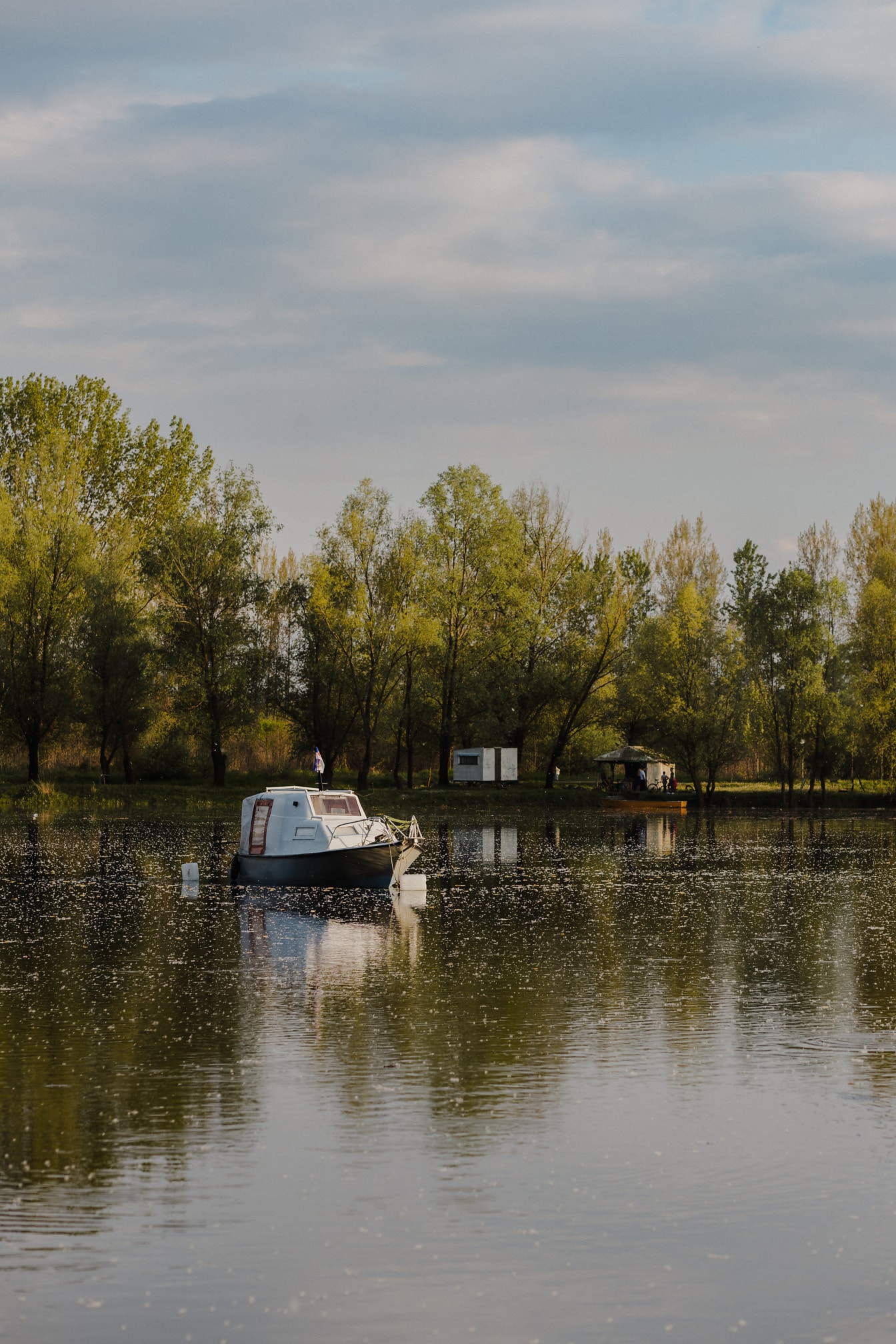 Liten hvit fiskebåt på innsjøen om våren