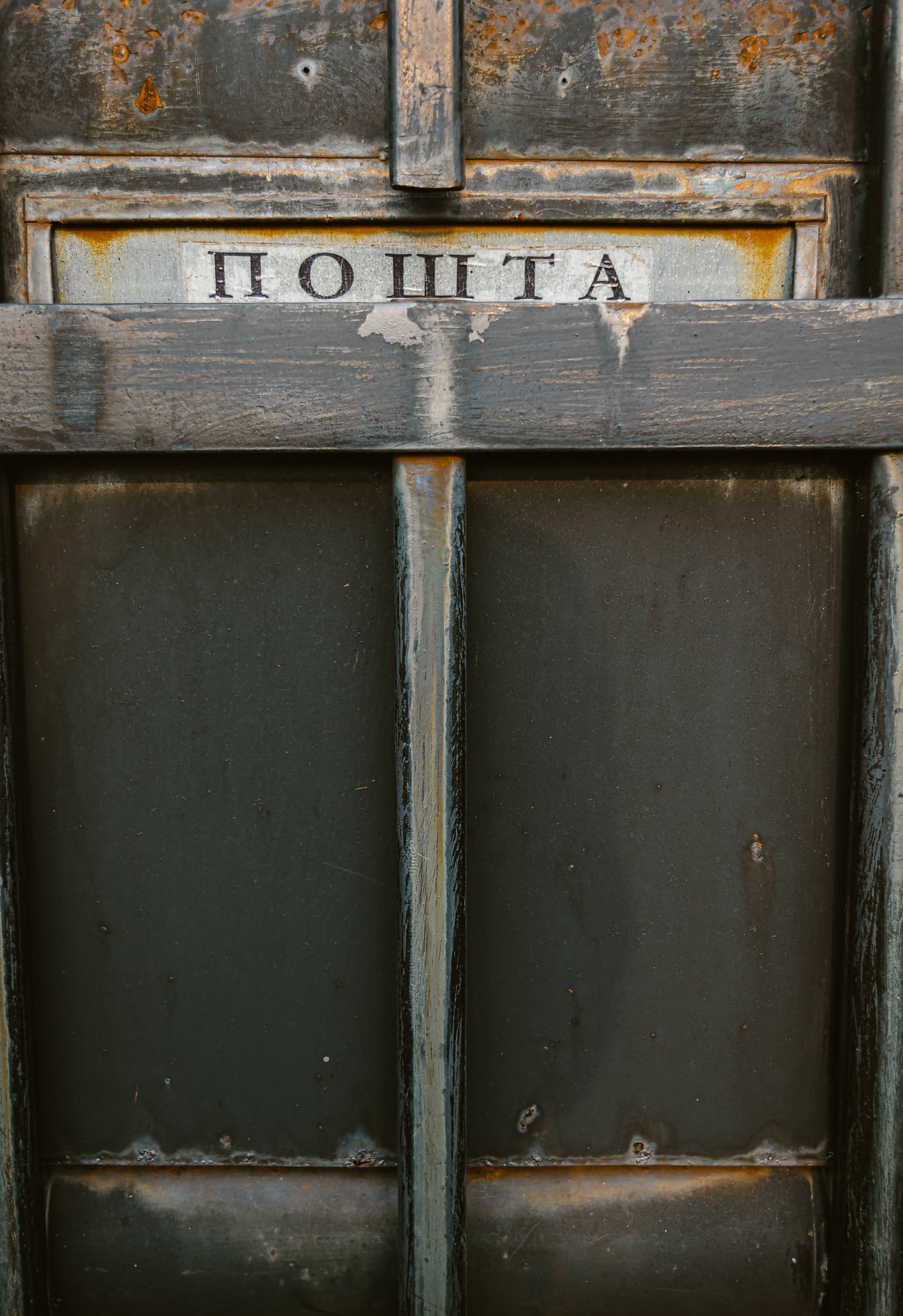 Nærbillede af sort metalpostkasse med kyrillisk tekst