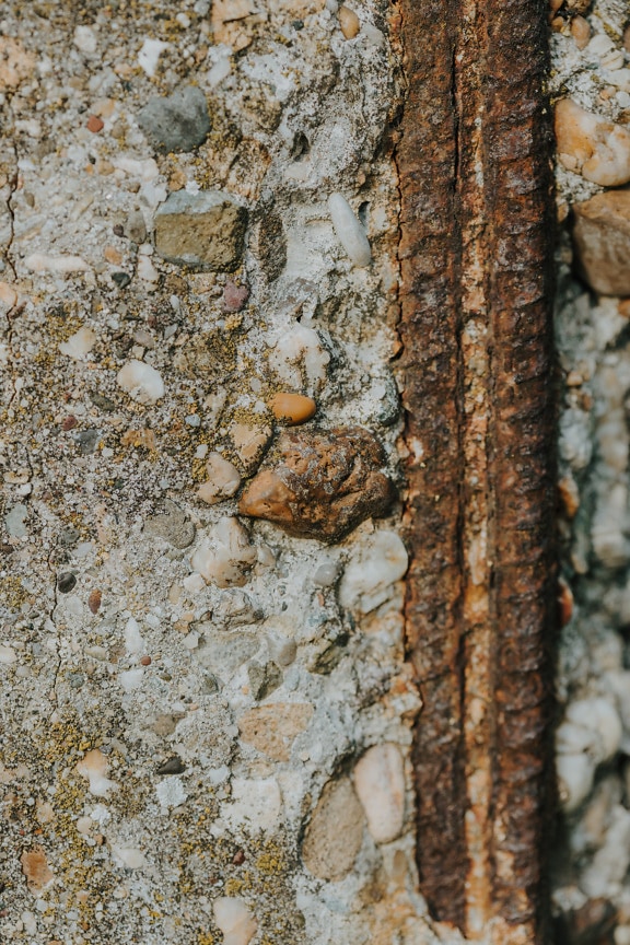 Rusty cast iron rod in old decay concrete texture
