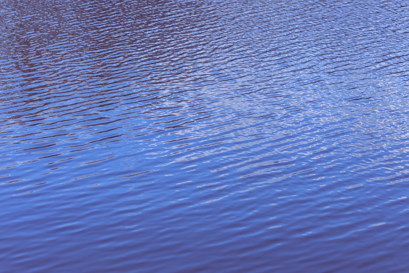 Φωτεινή μωβ-μπλε επιφάνεια ήρεμου νερού