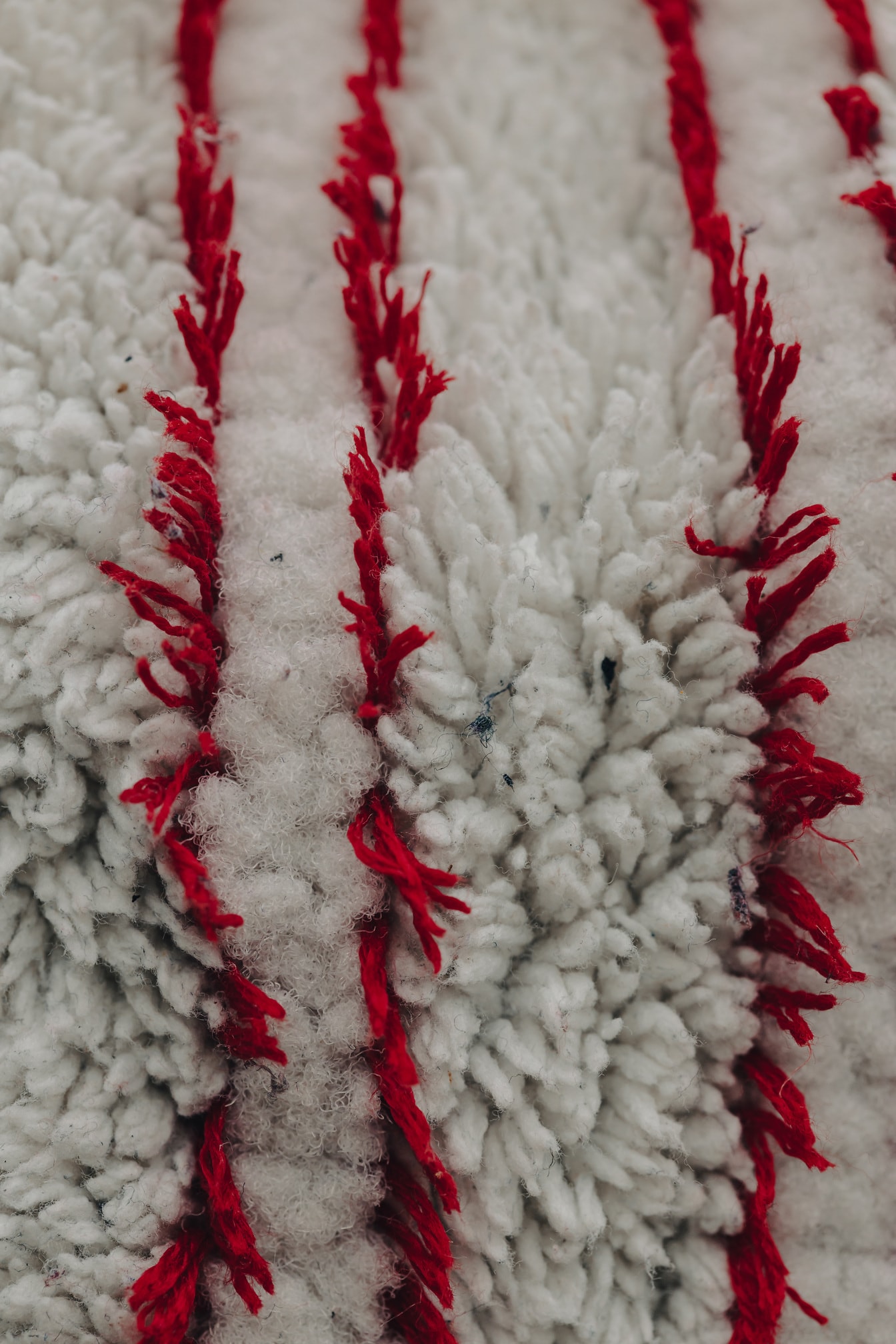 Tamnocrvene okomite linije vlakana u teksturi bijele vune
