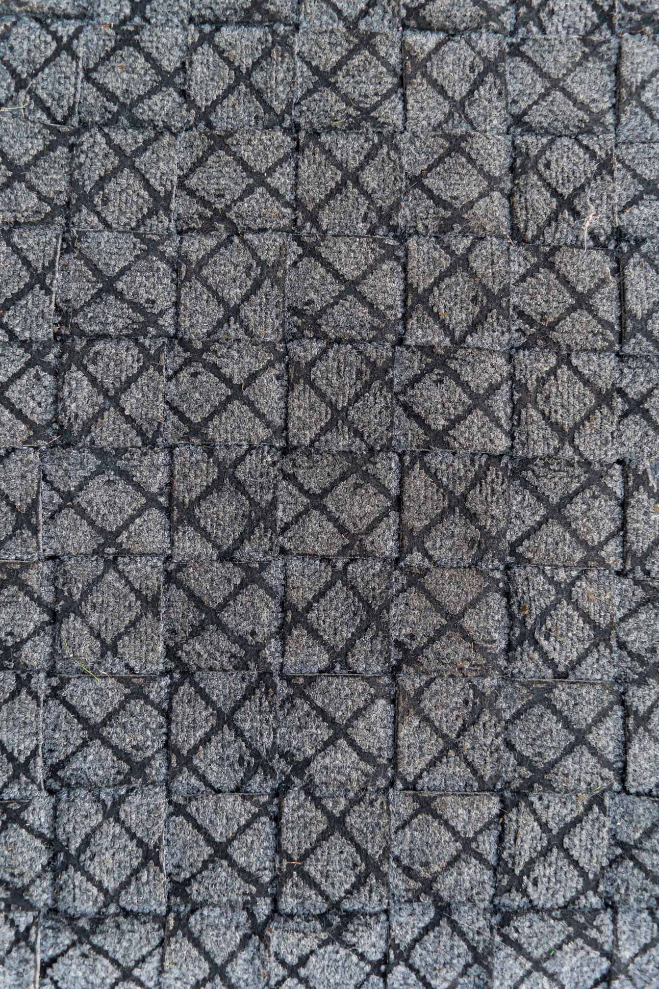 Nærbilde av dørmatte i polyester med svarte og grå linjer