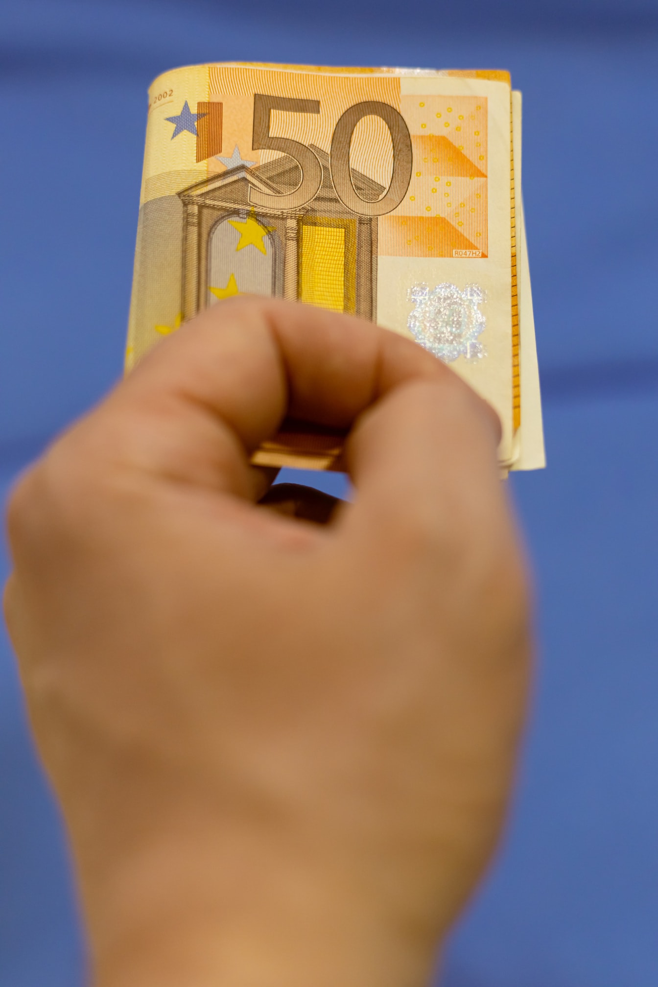 Ręka trzymająca papierowe pieniądze o nominale 50 euro