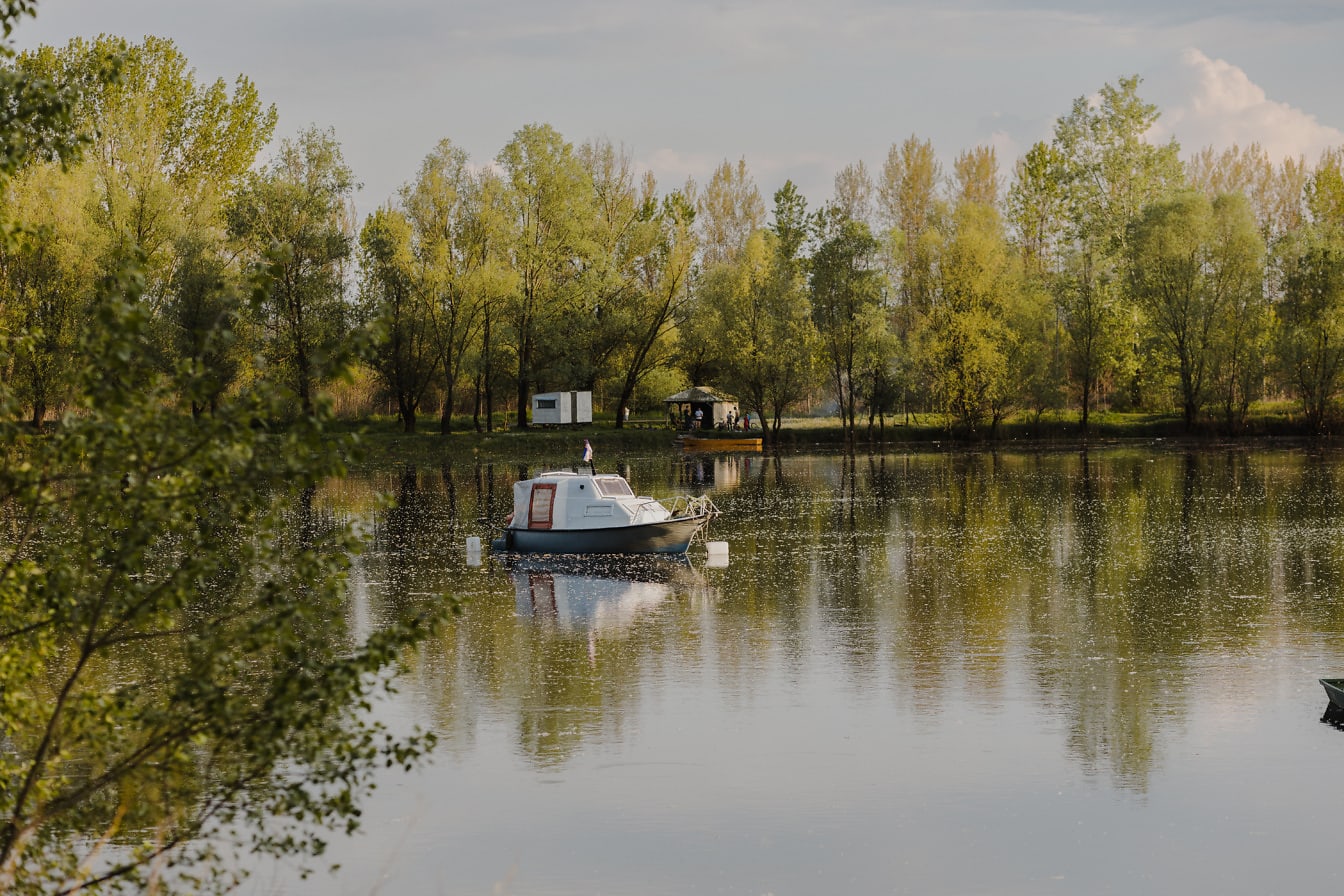 Идиллический весенний пейзаж на берегу озера с небольшой рыбацкой лодкой