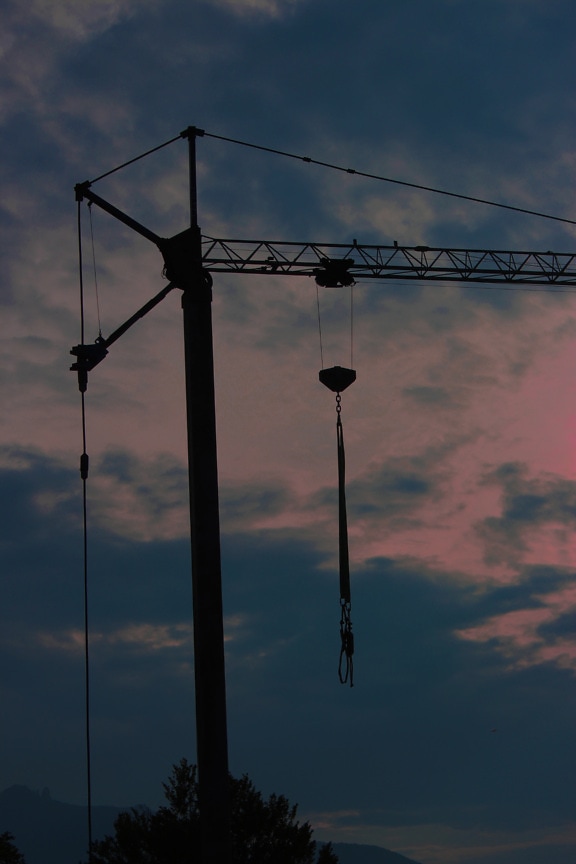 Silhouette of industrial crane machine with twilight sky
