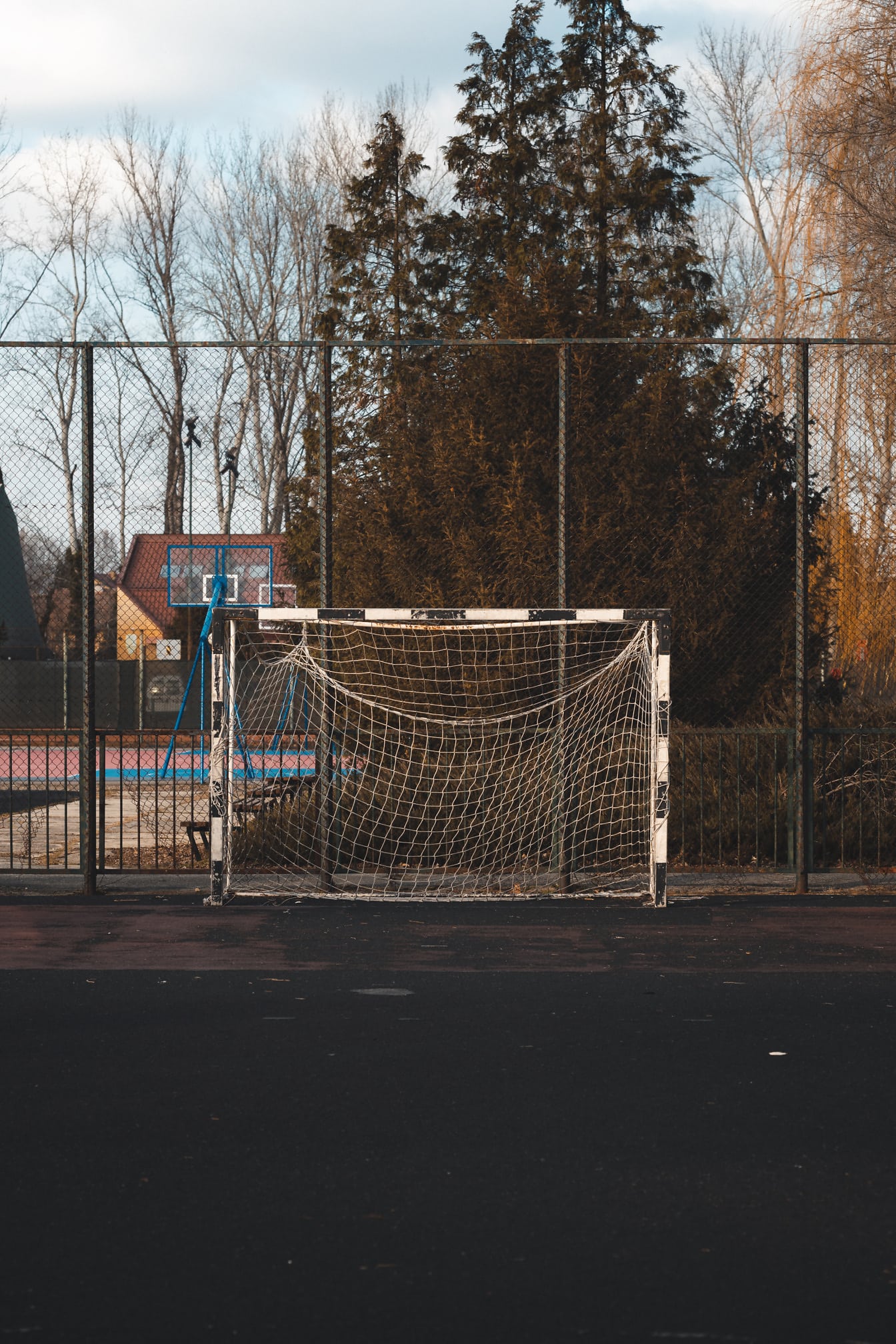 Prázdna futbalová bránka s basketbalovým ihriskom v pozadí