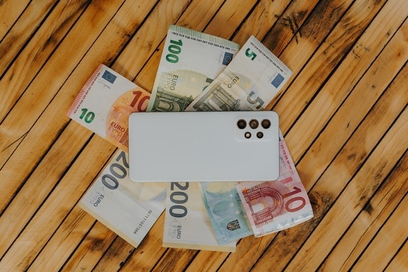 Biały telefon komórkowy na papierowych banknotach euro