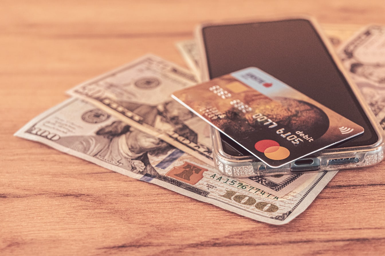 Kreditkort med mobiltelefon och dollarkontanter