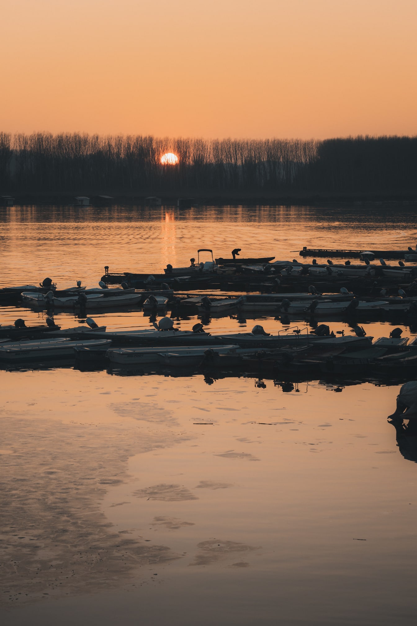 Água congelada no porto com silhueta de barcos de pesca ao amanhecer