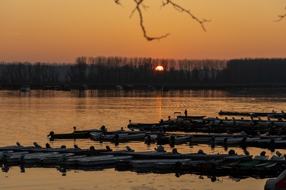 Sylwetka łodzi rybackich w porcie o zachodzie słońca nad jeziorami