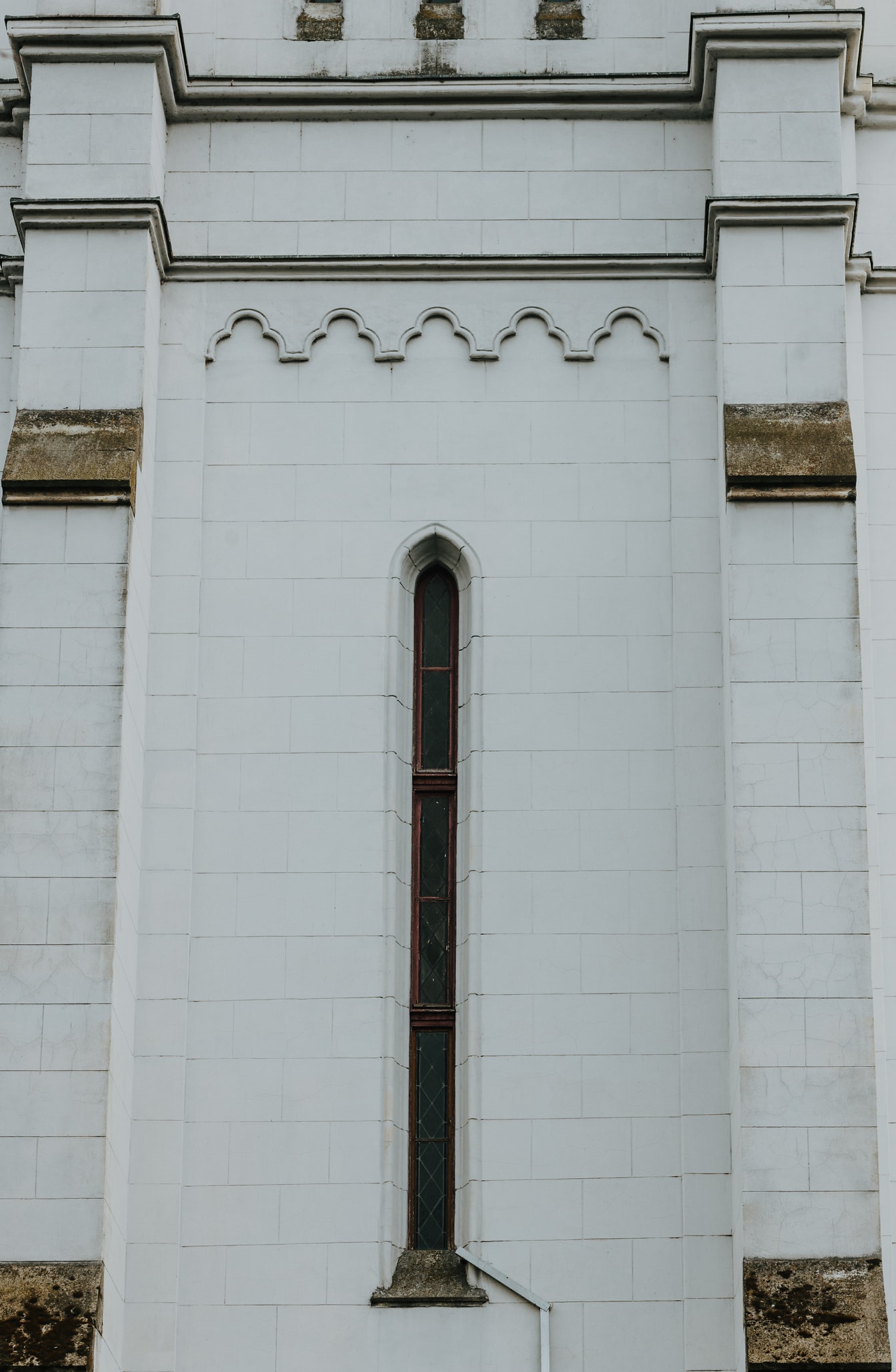 Hohes, schmales gotisches Fenster an weißer Marmorwand