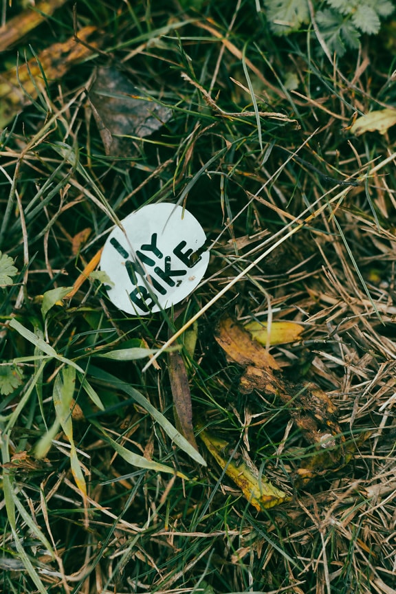 Garbage black and white paper sticker with text in grass