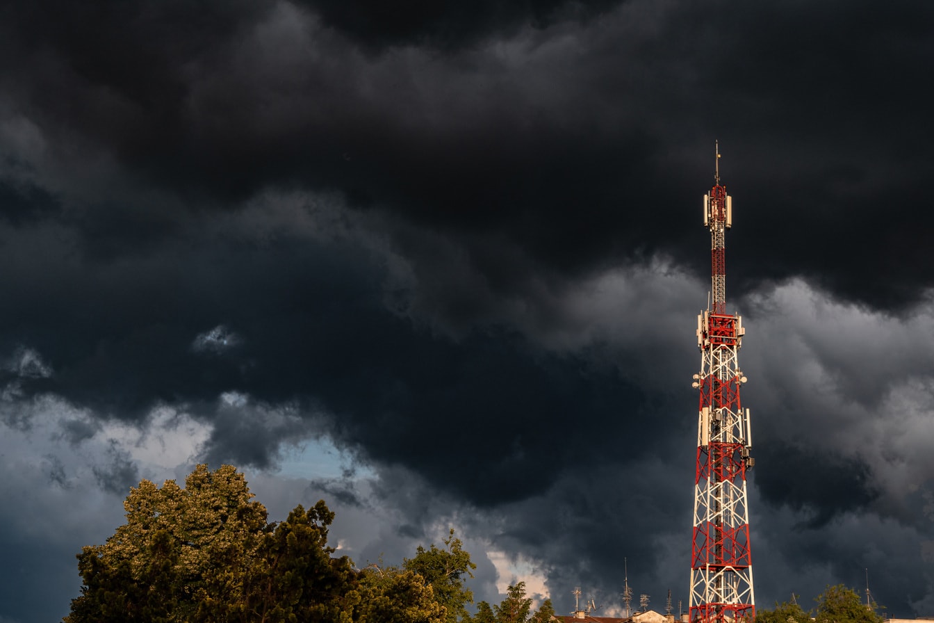 Телекоммуникационная башня на фоне темно-синих драматических облаков