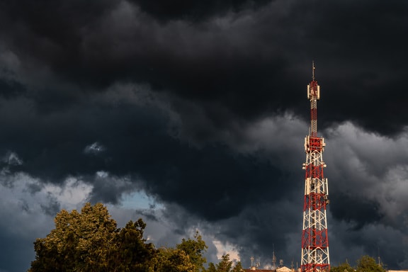 Telecommunication tower with dark blue dramatic clouds background