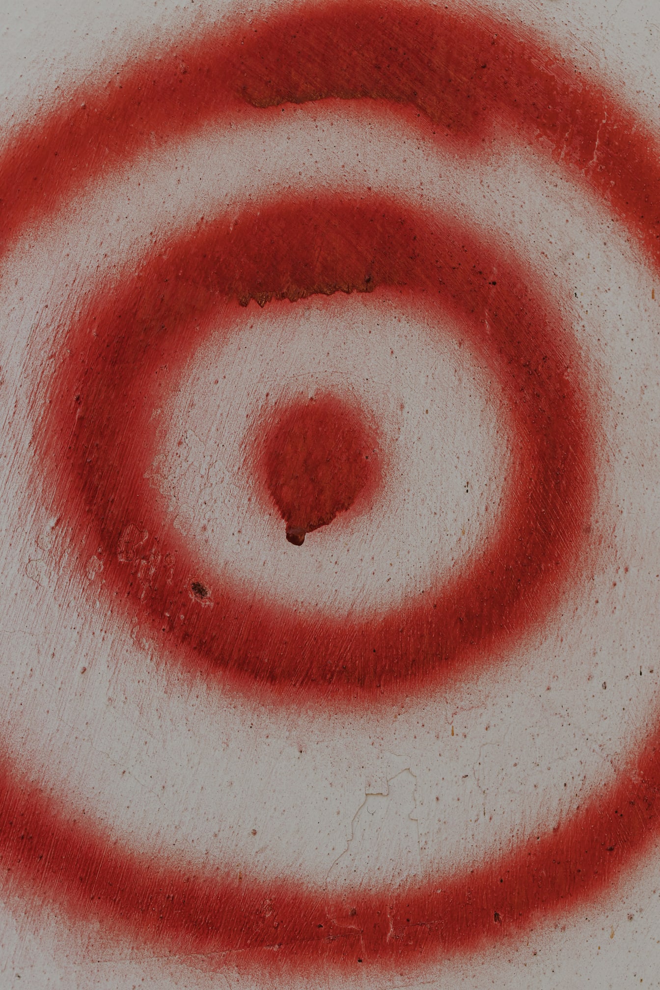 Círculos de pintura vermelho-escuro na textura de close-up bege da parede suja