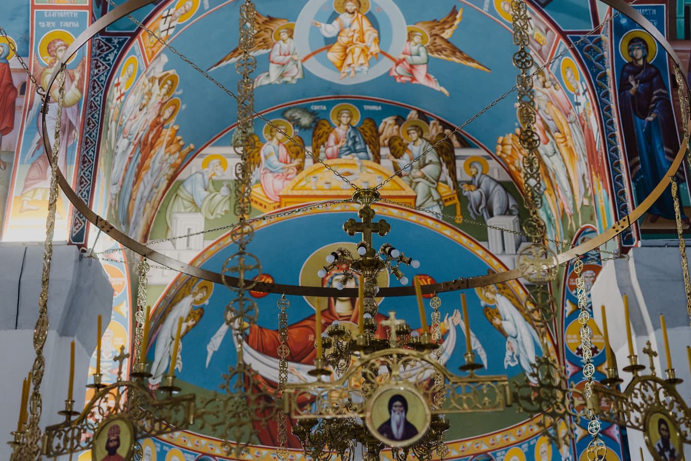 Stor lysekrone med lysestaker hengende fra taket i ortodoks kirke