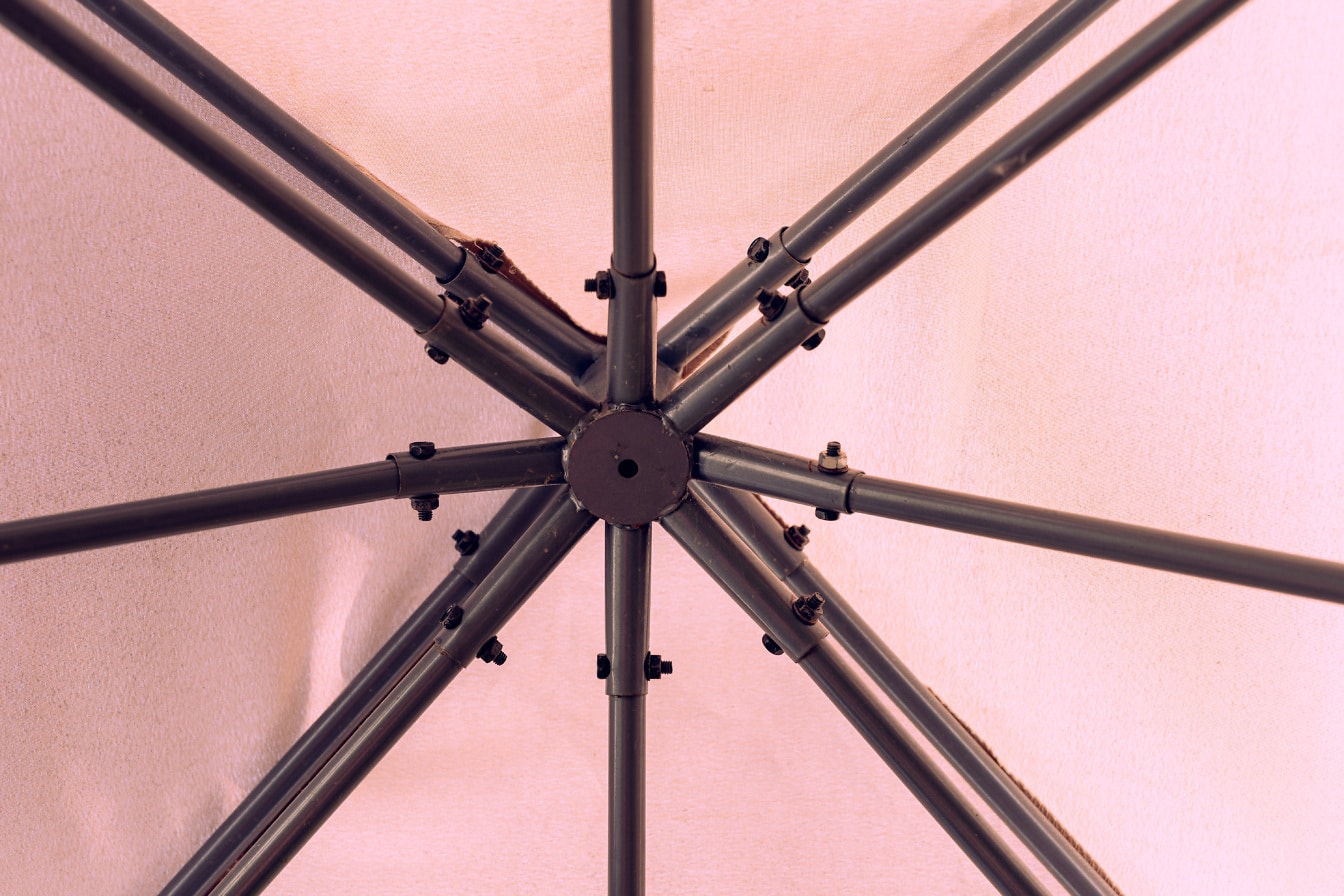 Detail kovové konstrukce deštníku s narůžovělým plátnem