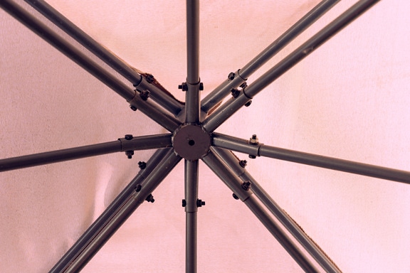 분홍빛이 도는 캔버스가 있는 우산의 금속 구조 클로즈업