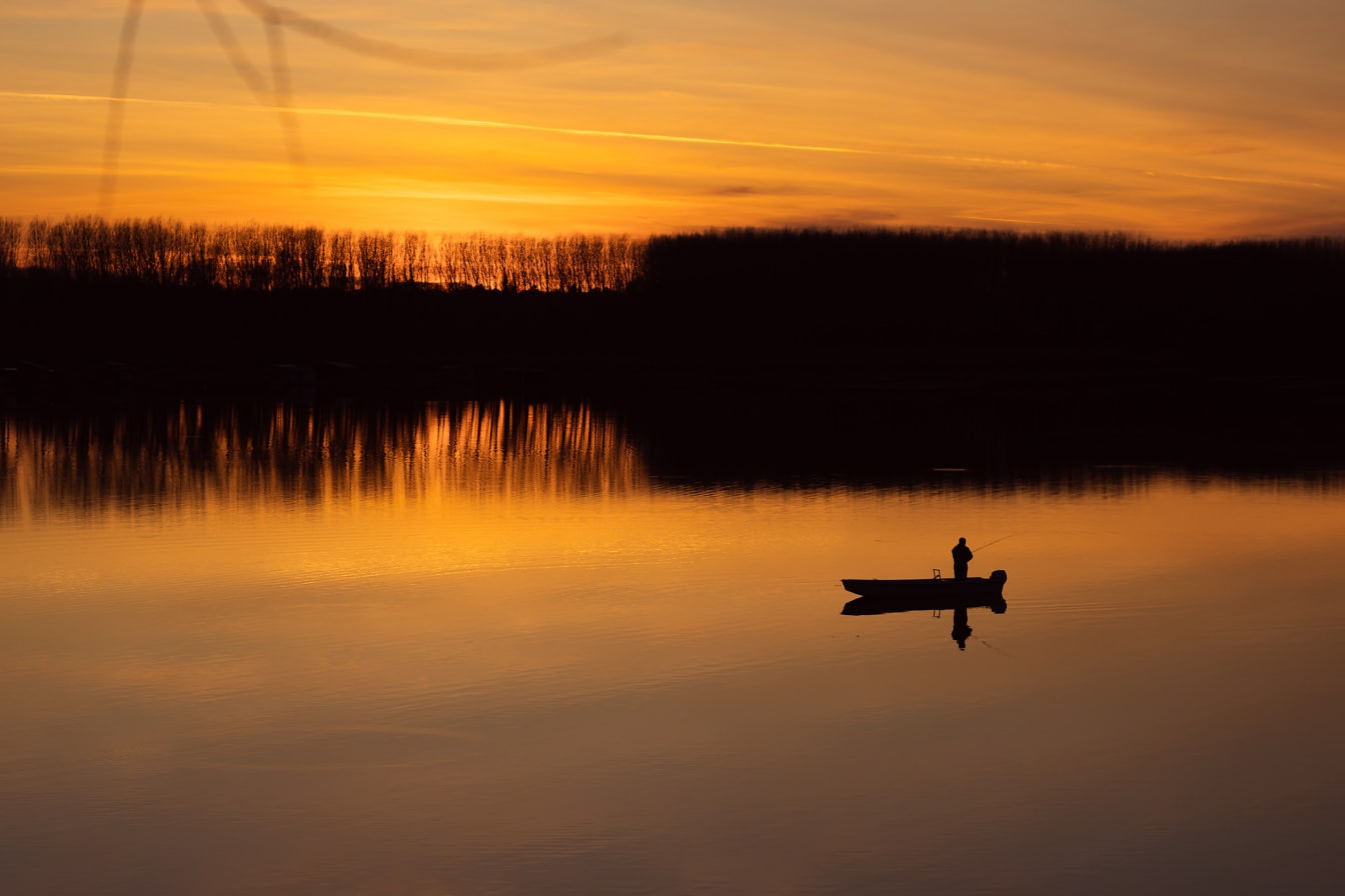 Majestätische orange-gelbe Sonnenuntergangsspiegelung auf ruhigem Seewasserspiegel