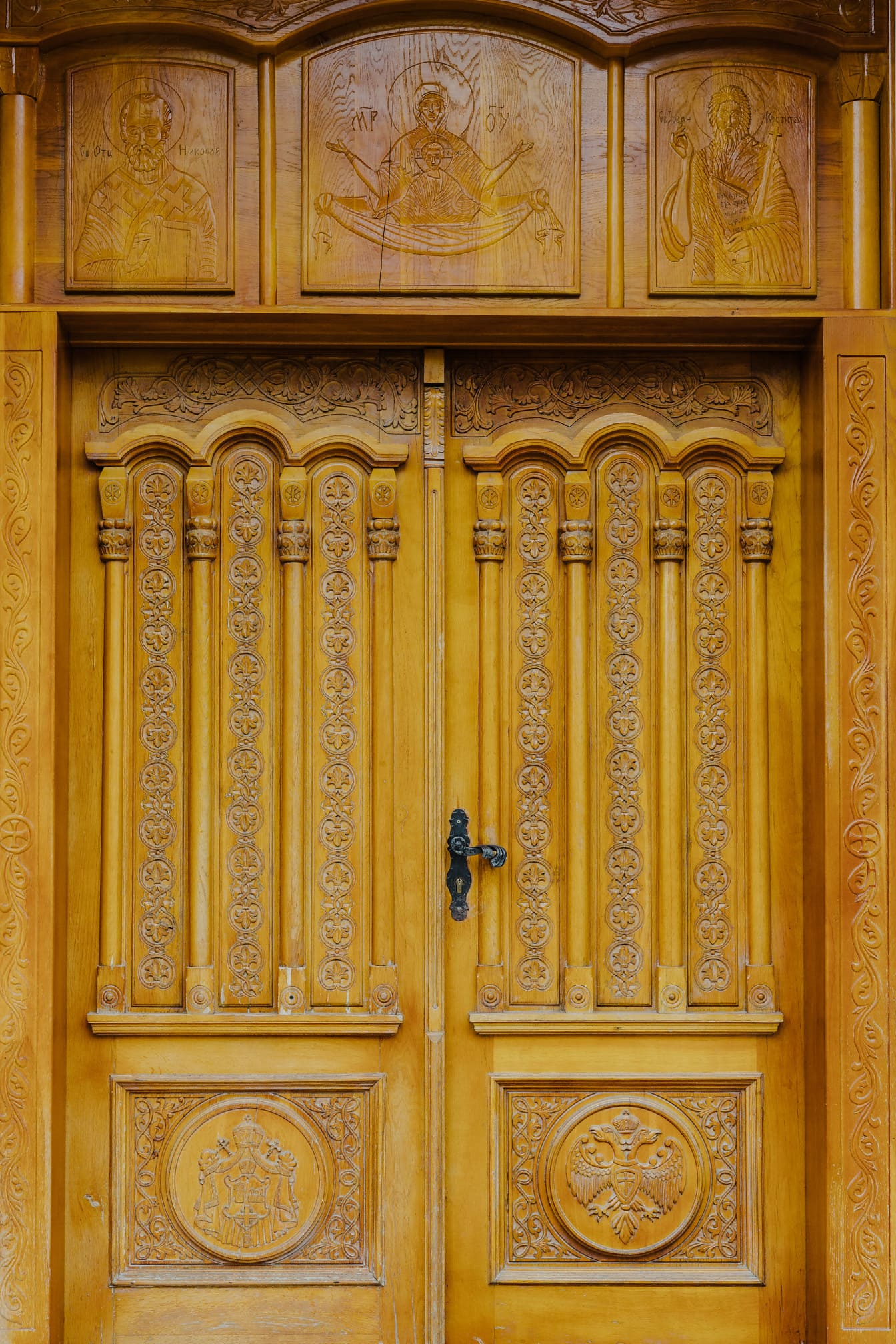 Ortodox kolostor fából készült bejárati ajtaja szent faragványokkal