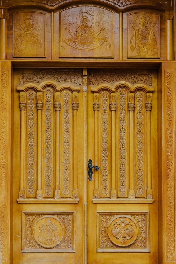 Wooden front door of orthodox monastery with saint carvings