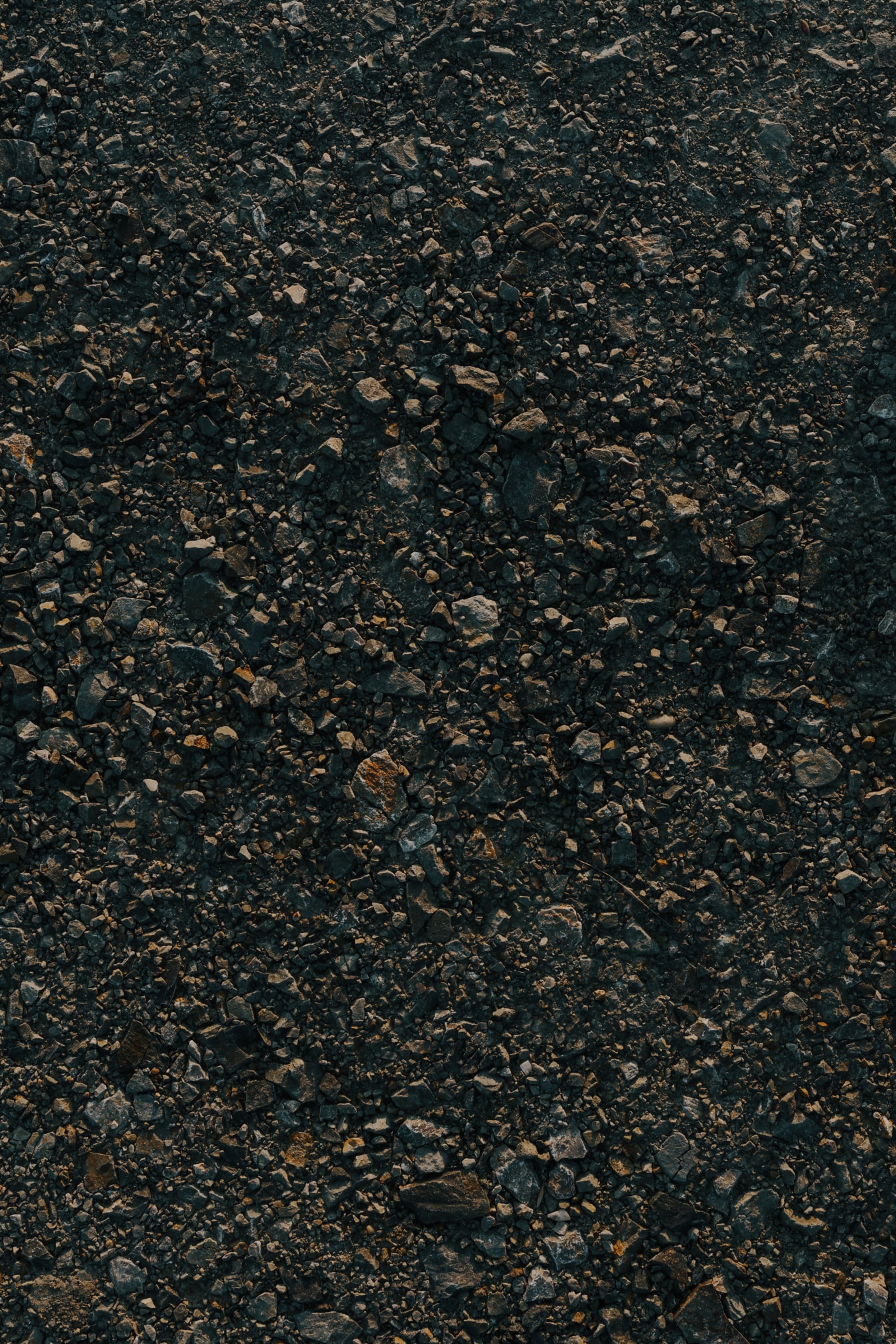 Seixos de granito escuro na textura áspera do solo