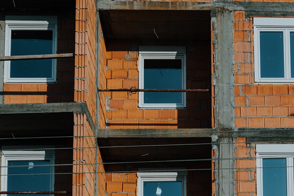 Fasade av bygning i konstruksjon med vinduer og balkong