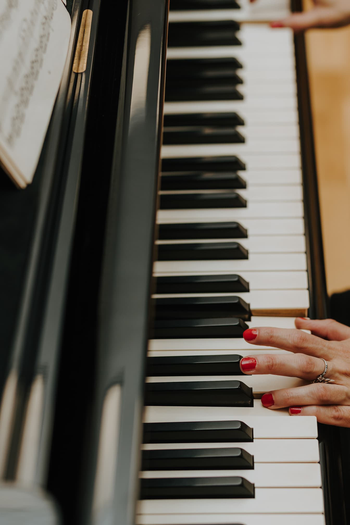 Músico con esmalte de uñas rojo oscuro tocando el piano