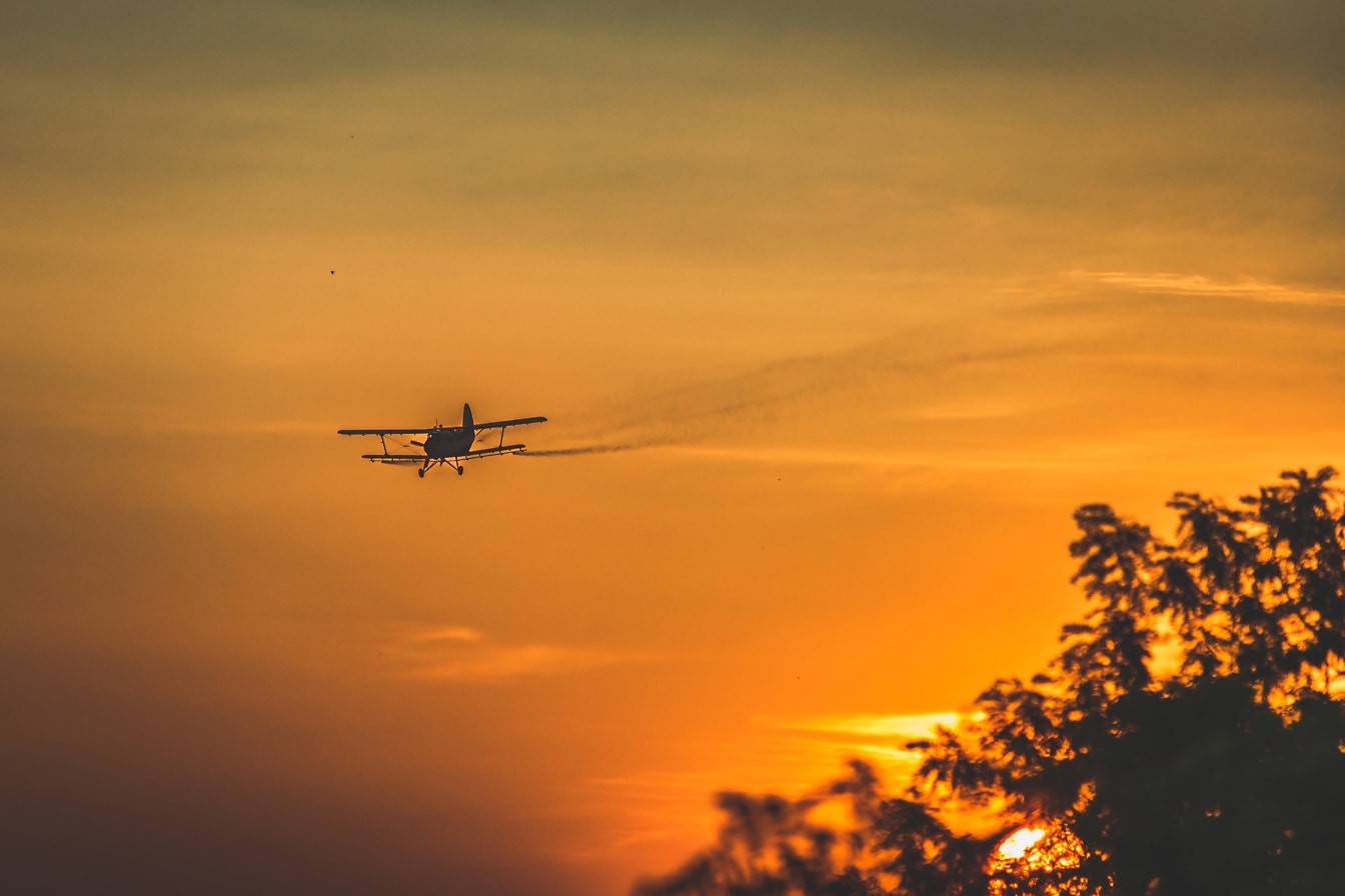 ภาพเงาของเครื่องบินสองชั้นบนท้องฟ้าสีเหลืองส้มยามพระอาทิตย์ตกดิน