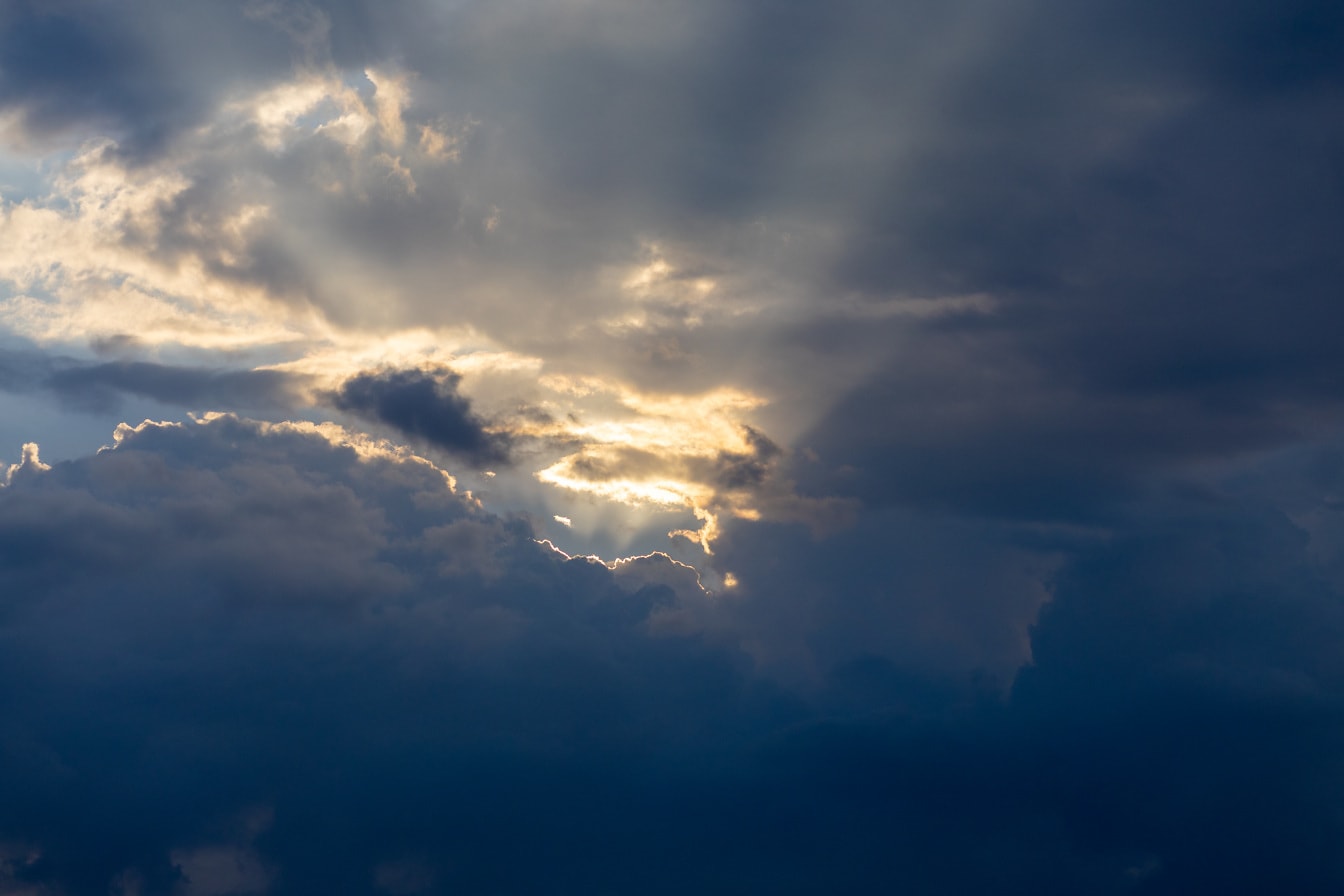 Nuvole temporalesche blu scuro con raggi di sole