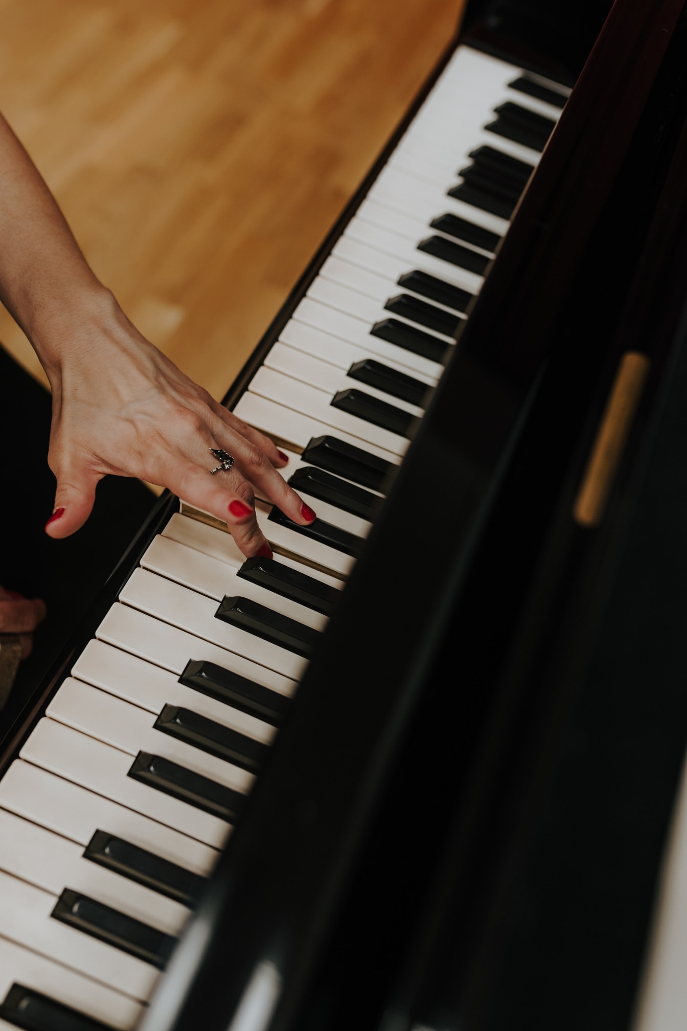 Женщина играет на пианино крупным планом красного лака для ногтей на пальцах