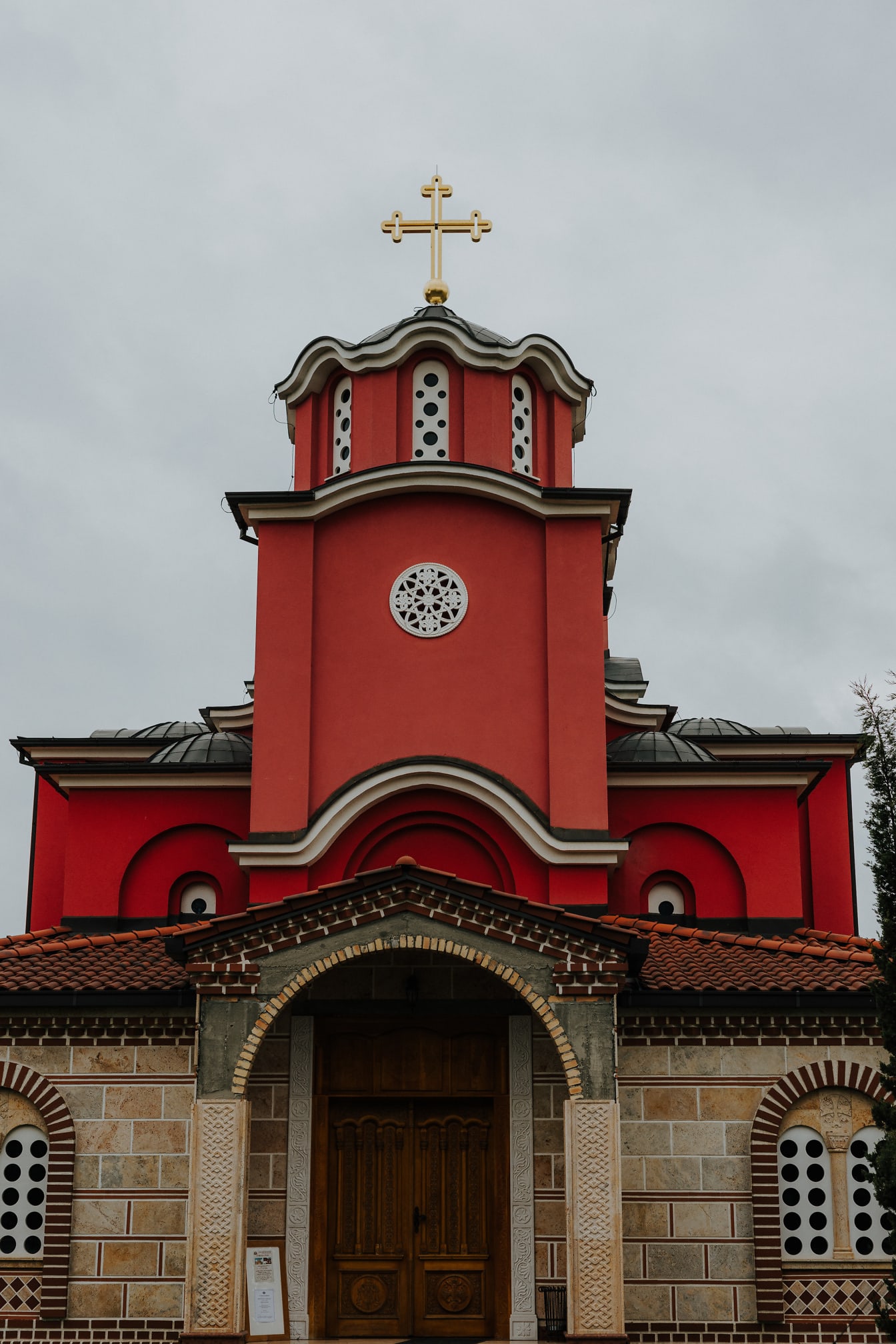 Turnul bisericii roșu închis cu cruce de aur pe biserica ortodoxă
