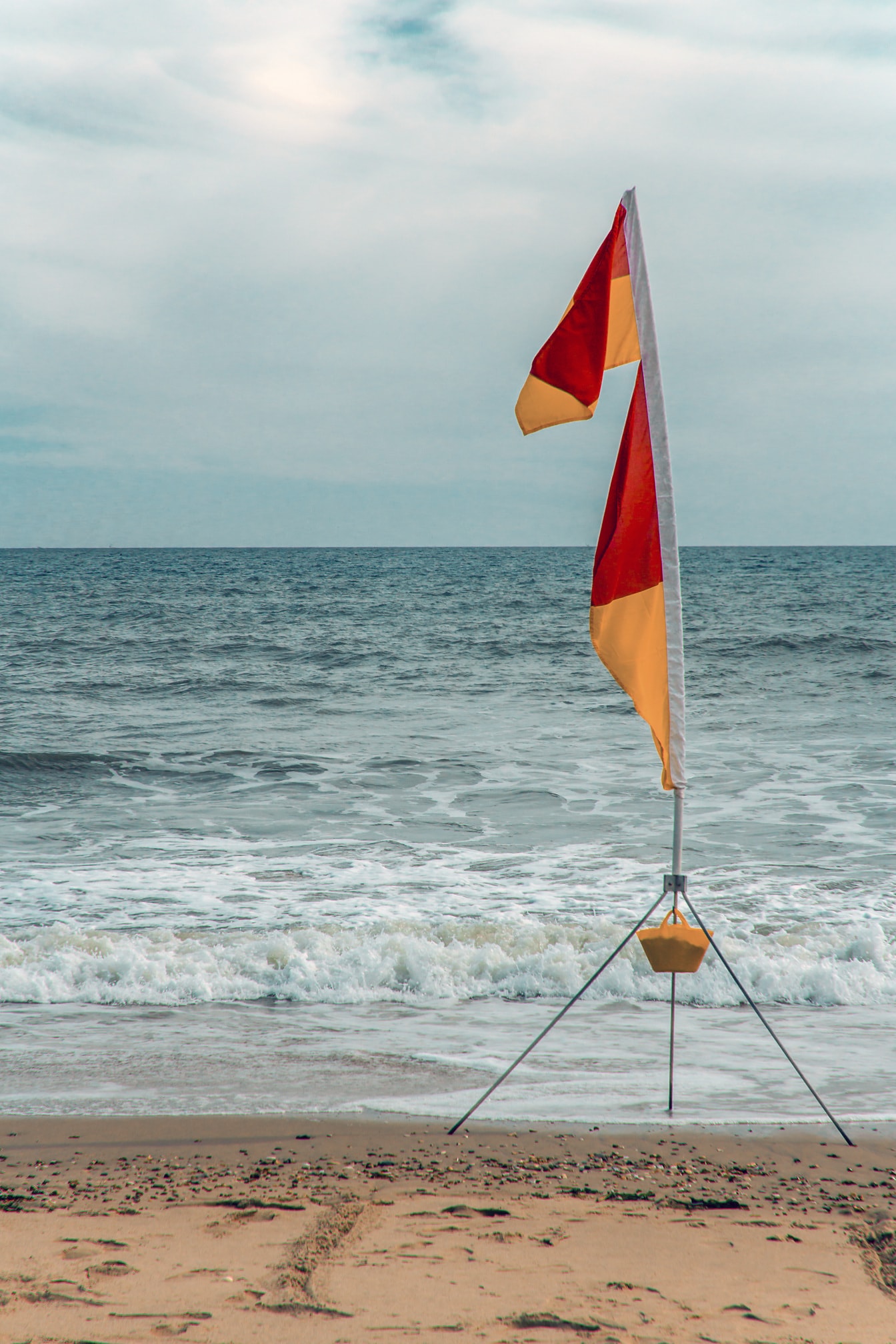 Surffimerkki oranssinkeltainen kangaslippu kepissä rannalla