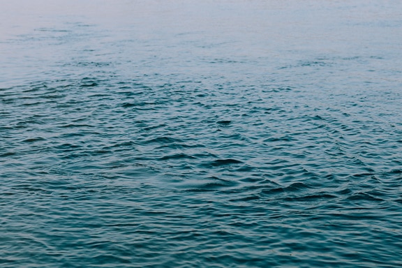 Azure blue waves ripple on calm ocean horizon