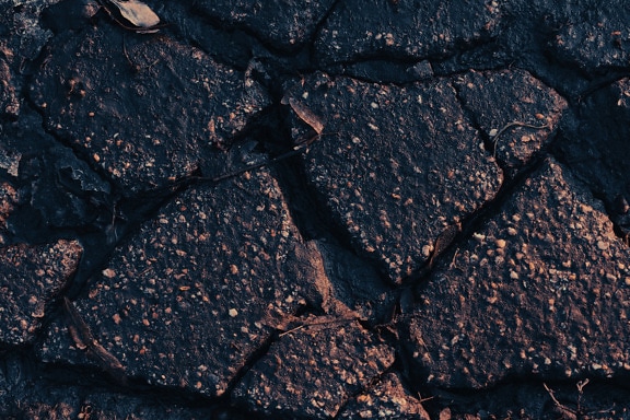 地面の質感に黒い濡れた粗いコンクリート部品