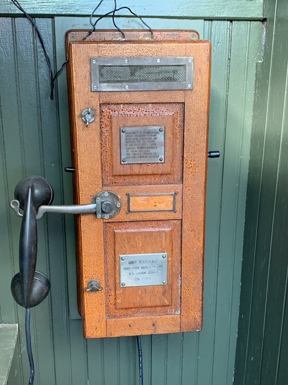 Starožitný nástěnný telefon v dřevěné krabičce v muzeu