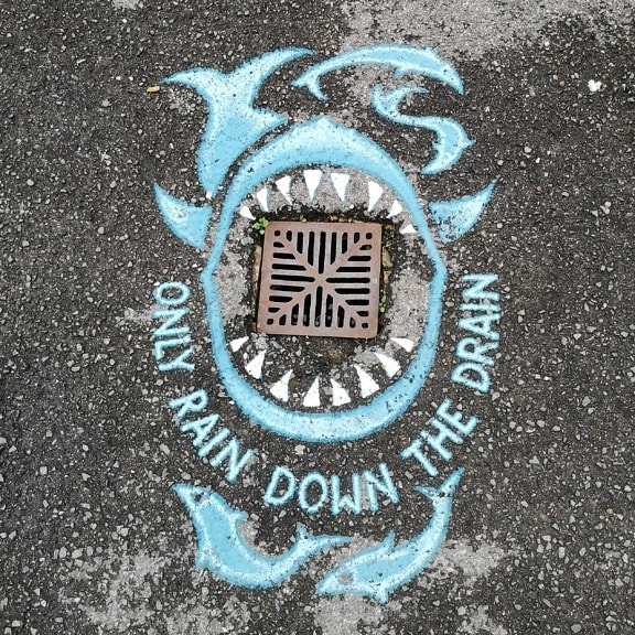 Street art graffiti on asphalt with sewage manhole