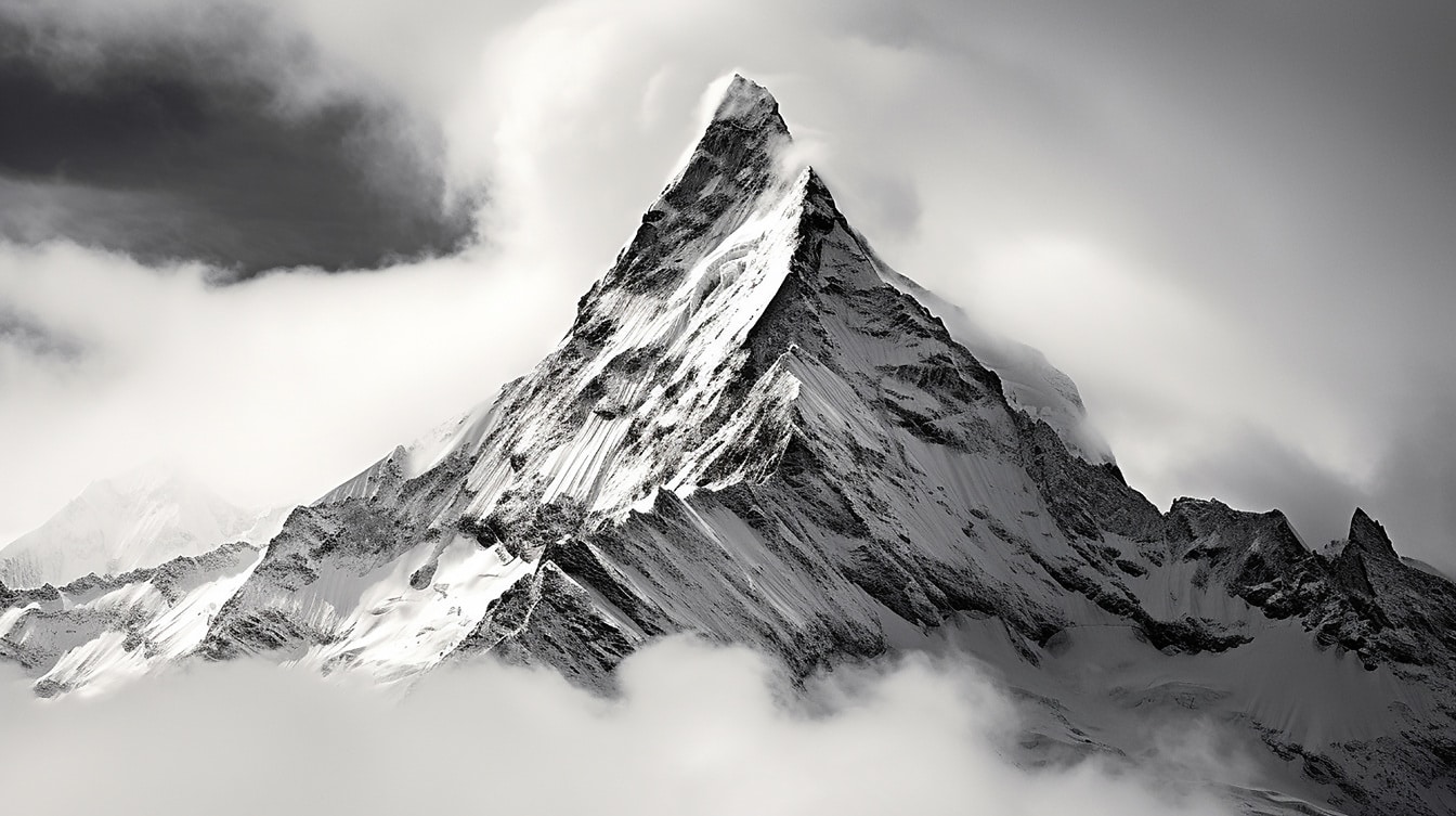 Zamarznięty szczyt górski w białych chmurach monochromatyczna fotografia