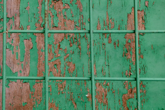 Peinture brute vert foncé sur planches de bois avec grille métallique